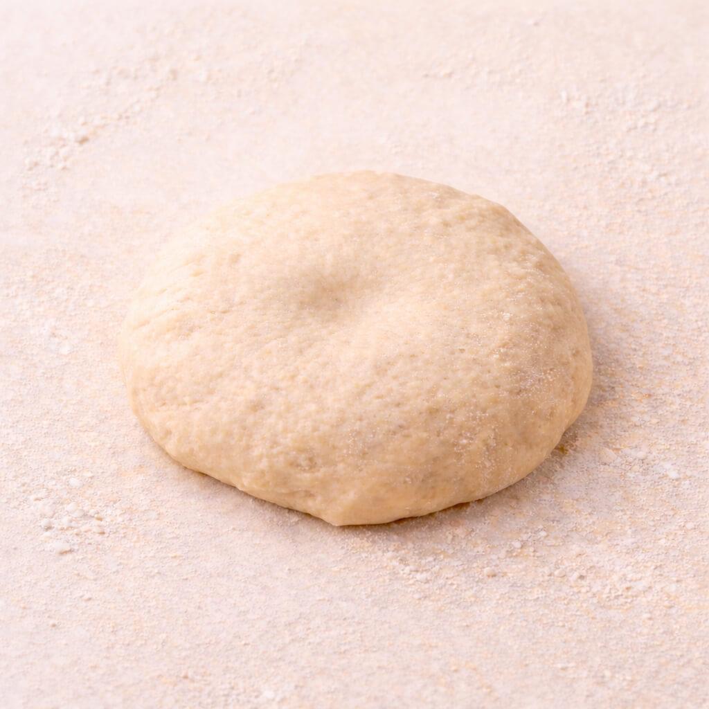 Proofed dough ball with a very shallow poke mark that is already fading.